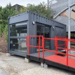 External view of container coffee shop with accessibility ramp and floor-length window.